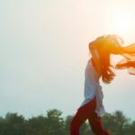 夕日に髪をなびかせる女性